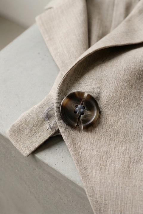 Close-up of a linen blazer with a cracked horn button